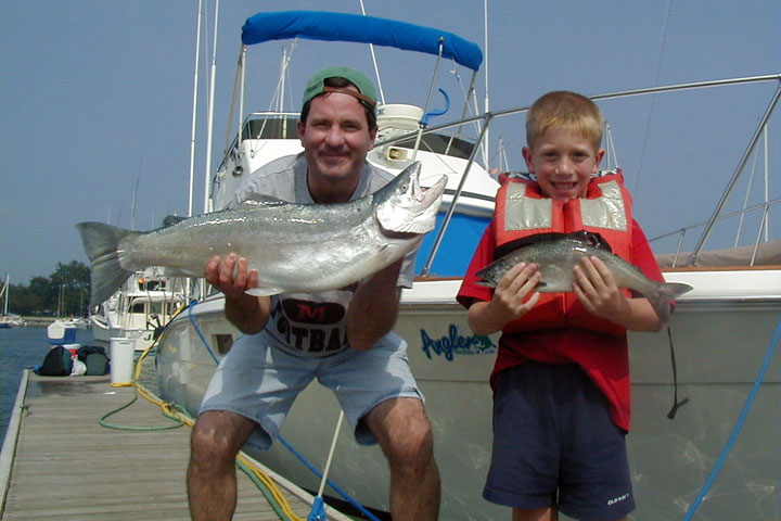Father and Son holding their fish: a Big Lake Trout and a smaller Brown Trout, caught in Lake Michigan.