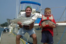 Father and Son holding their fish: a Big Lake Trout and a smaller Brown Trout, caught in Lake Michigan.